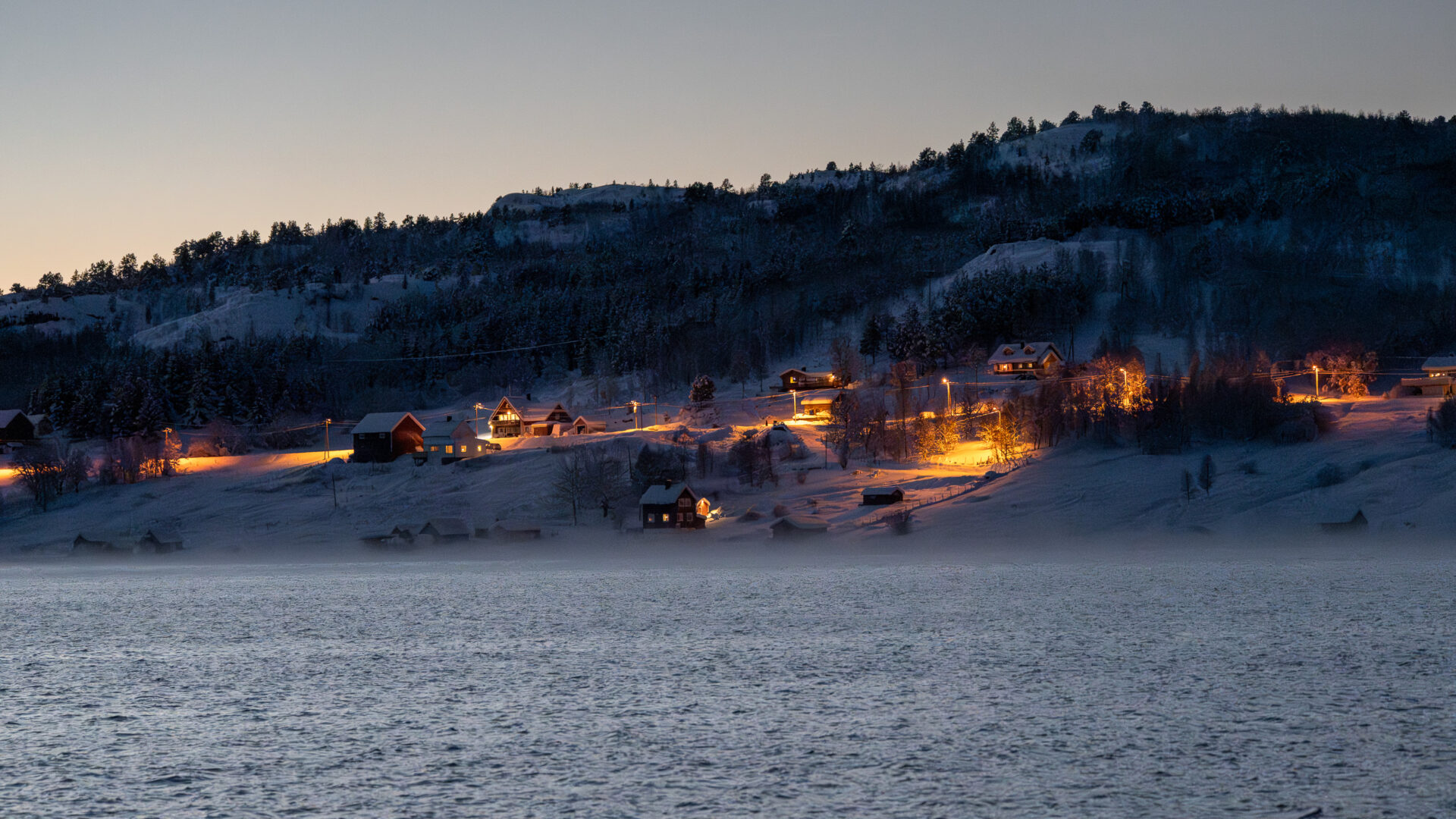 Snow-covered mountains reflected in fjord water